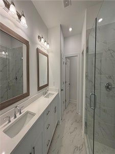 Primary bathroom has double vanities, large glass enclosed shower with custom tile. New Home in Cumming, GA